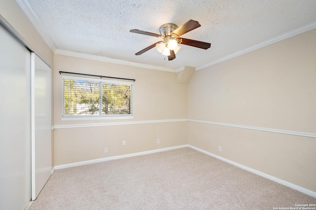 spare room featuring light carpet, ceiling fan, ornamental molding, and a textured ceiling