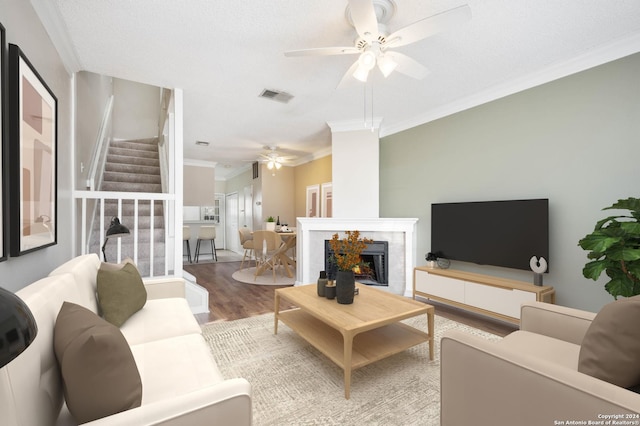 living room featuring a tiled fireplace, ceiling fan, hardwood / wood-style floors, and crown molding