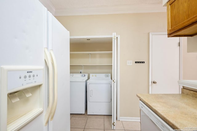 laundry area with light tile patterned floors, crown molding, and washing machine and clothes dryer