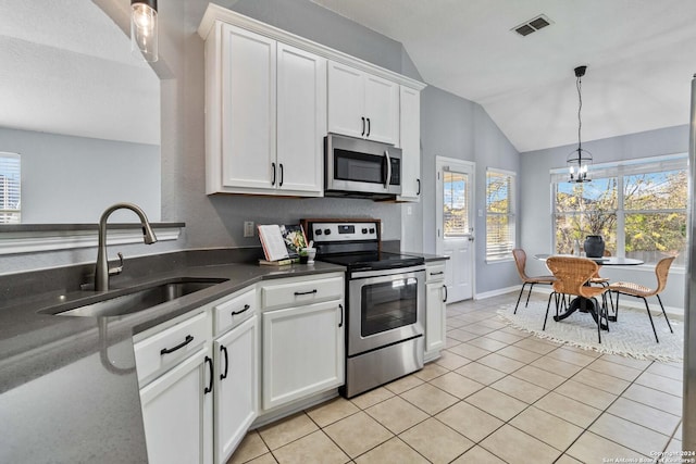 kitchen with stainless steel appliances, vaulted ceiling, sink, white cabinetry, and hanging light fixtures