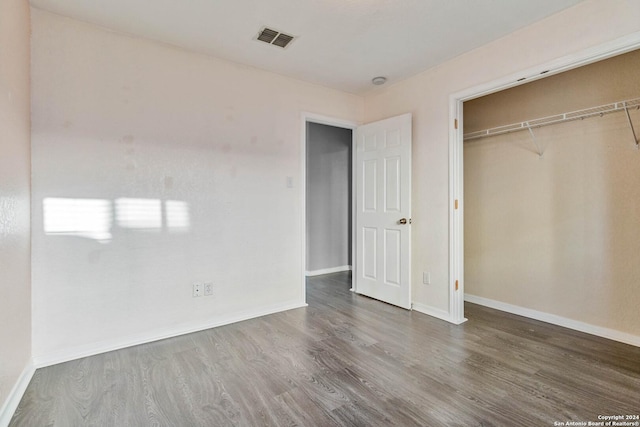 unfurnished bedroom featuring dark hardwood / wood-style floors and a closet