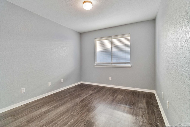 spare room with dark hardwood / wood-style floors and a textured ceiling