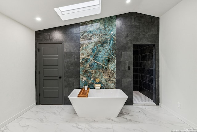 bathroom with a bath, tile walls, and vaulted ceiling with skylight