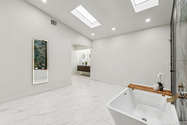 bathroom with vaulted ceiling with skylight, vanity, and a bathing tub