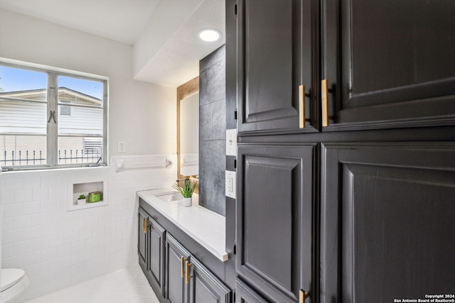 bathroom with tile patterned flooring, vanity, toilet, and tile walls