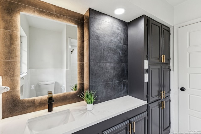 bathroom with vanity, toilet, and tile walls