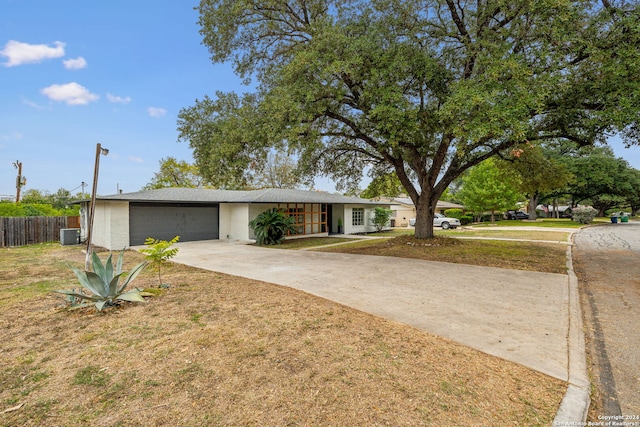 ranch-style home with central AC unit, a garage, and a front lawn