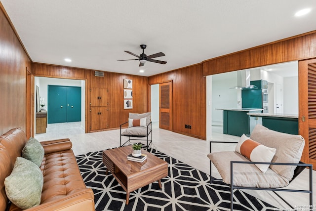 living room featuring ceiling fan and wooden walls