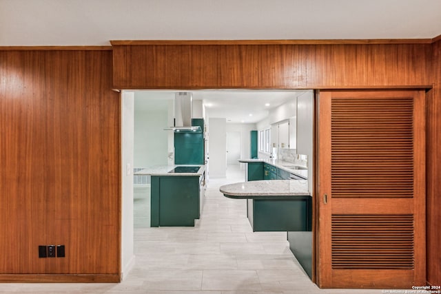 kitchen featuring light stone countertops, kitchen peninsula, green cabinets, and exhaust hood