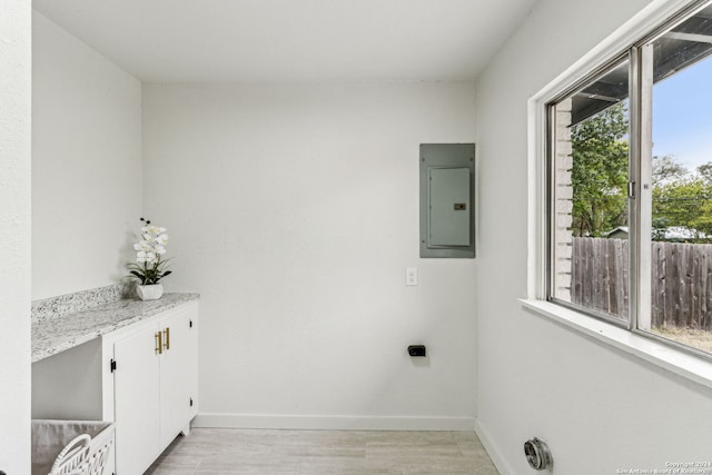 laundry room featuring electric dryer hookup, electric panel, plenty of natural light, and light hardwood / wood-style flooring