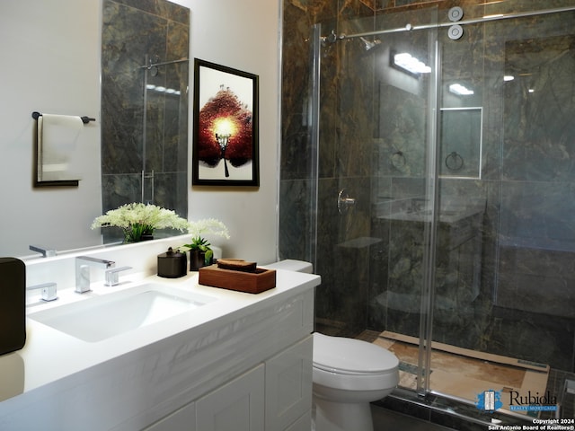 bathroom featuring a shower with door, vanity, and toilet