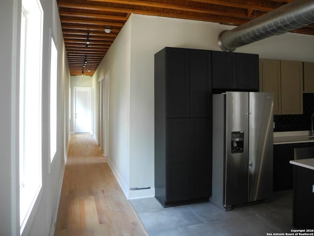 kitchen with stainless steel refrigerator with ice dispenser, gray cabinets, tasteful backsplash, and light hardwood / wood-style floors