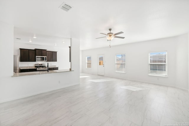 unfurnished living room featuring ceiling fan and sink