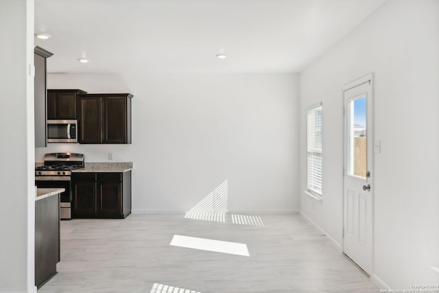 kitchen featuring light stone countertops, dark brown cabinets, stainless steel appliances, and light hardwood / wood-style floors