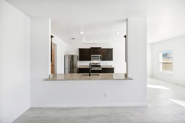 kitchen with light stone counters, sink, kitchen peninsula, and stainless steel appliances