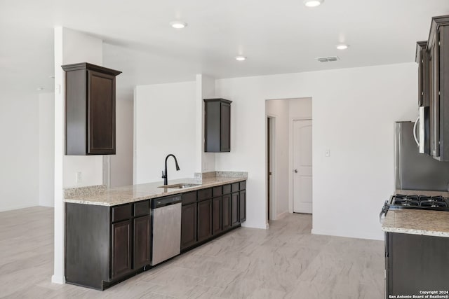 kitchen featuring light stone counters, sink, dark brown cabinets, and appliances with stainless steel finishes