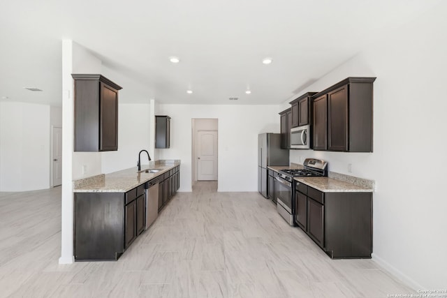 kitchen with light stone countertops, sink, stainless steel appliances, and dark brown cabinets