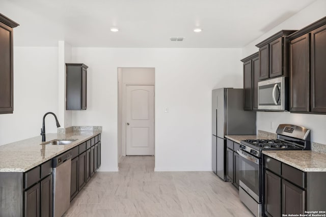 kitchen featuring dark brown cabinetry, light stone countertops, sink, and appliances with stainless steel finishes