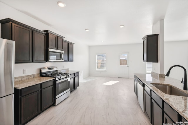 kitchen featuring dark brown cabinetry, light stone counters, sink, and stainless steel appliances