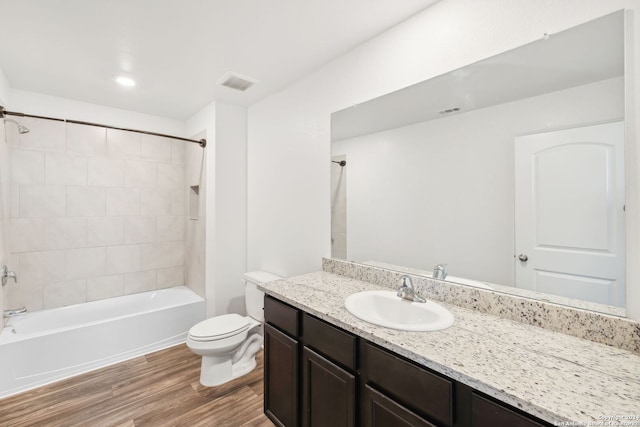 full bathroom featuring hardwood / wood-style floors, vanity, tiled shower / bath combo, and toilet