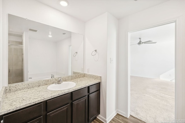 bathroom featuring hardwood / wood-style floors, ceiling fan, walk in shower, and vanity