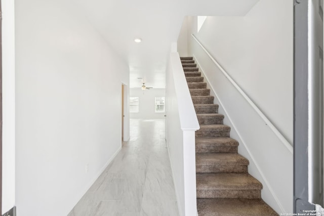 stairs featuring ceiling fan