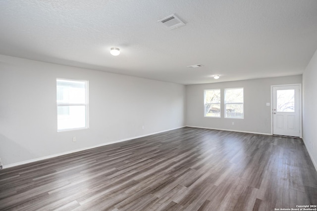 spare room featuring a textured ceiling and dark wood-type flooring