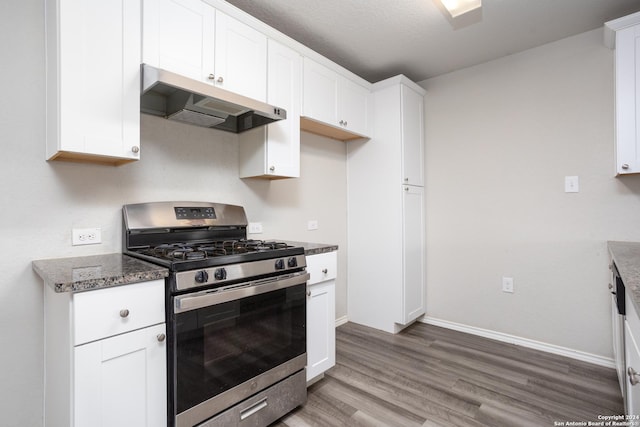 kitchen featuring gas stove, dark stone counters, a textured ceiling, white cabinets, and hardwood / wood-style flooring