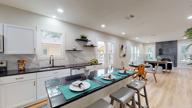 kitchen with white cabinetry, sink, dishwasher, and light hardwood / wood-style flooring