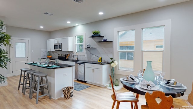 kitchen with sink, tasteful backsplash, light hardwood / wood-style flooring, white cabinets, and appliances with stainless steel finishes