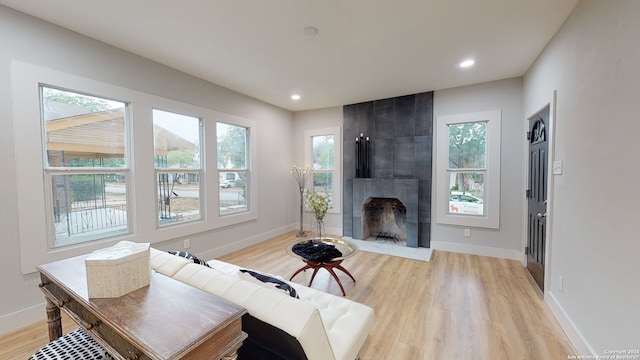 living room with a tile fireplace and light hardwood / wood-style flooring