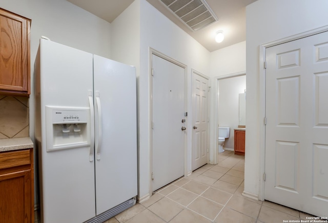 kitchen with white fridge with ice dispenser and light tile patterned flooring