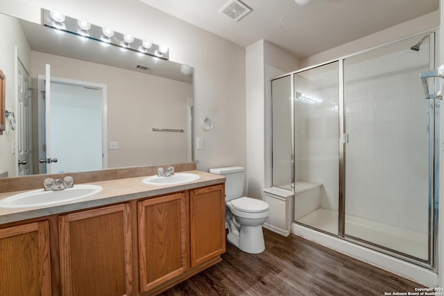 bathroom with hardwood / wood-style floors, vanity, toilet, and a shower with door