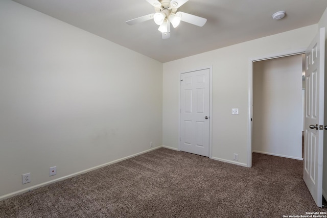 unfurnished bedroom with dark carpet and ceiling fan