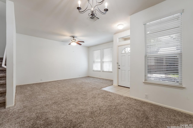 carpeted entrance foyer with ceiling fan with notable chandelier