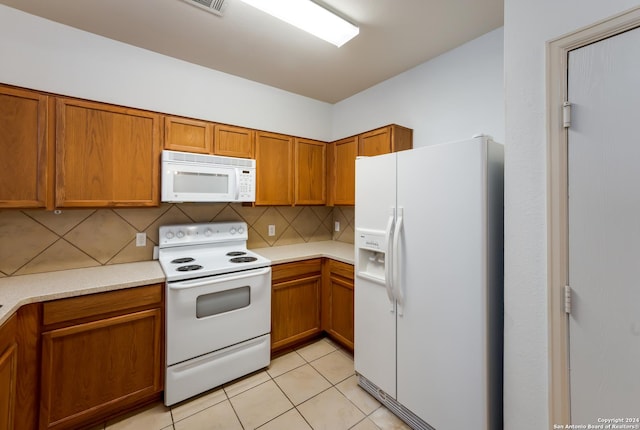 kitchen featuring decorative backsplash, light tile patterned floors, and white appliances