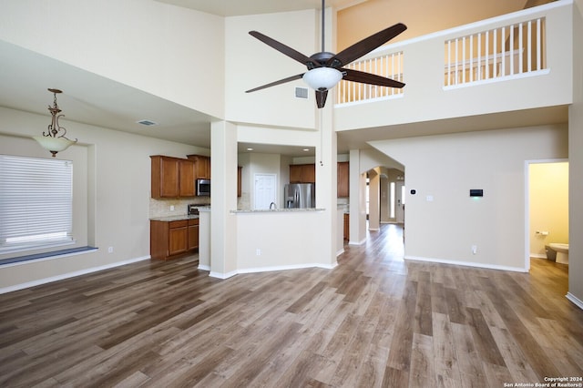 unfurnished living room with a high ceiling, hardwood / wood-style flooring, and ceiling fan