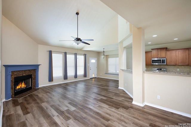 unfurnished living room with a high end fireplace, dark hardwood / wood-style flooring, vaulted ceiling, and ceiling fan