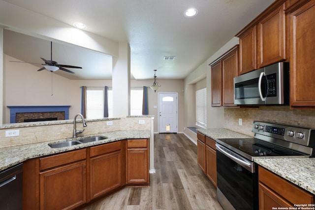 kitchen featuring sink, pendant lighting, appliances with stainless steel finishes, ceiling fan with notable chandelier, and light wood-type flooring