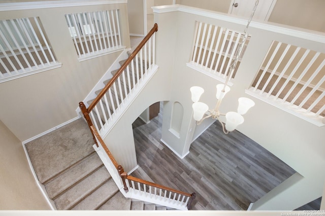 stairway with hardwood / wood-style floors and an inviting chandelier