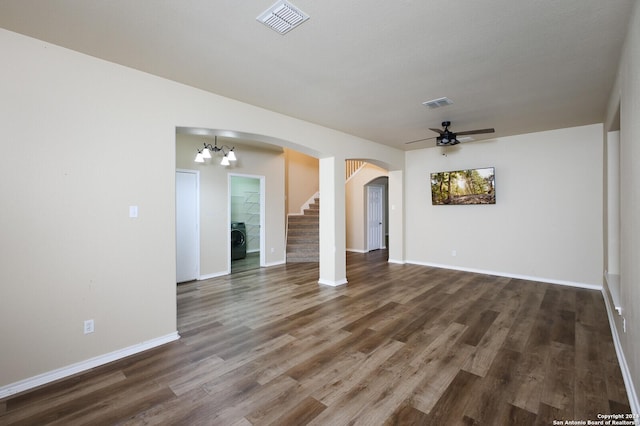 unfurnished living room featuring ceiling fan with notable chandelier, washer / dryer, and dark hardwood / wood-style flooring