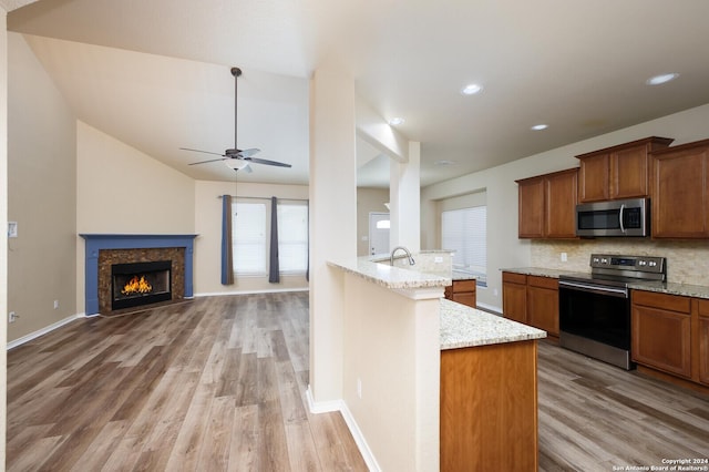 kitchen featuring backsplash, sink, light hardwood / wood-style flooring, light stone counters, and stainless steel appliances