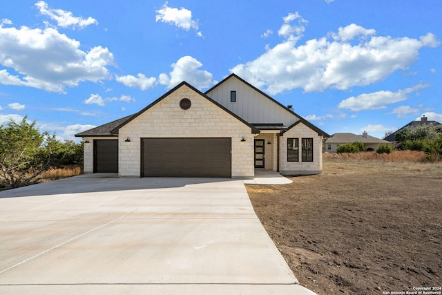 view of front of home featuring metal roof, an attached garage, driveway, board and batten siding, and a standing seam roof