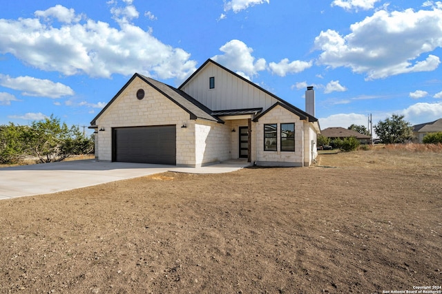 view of front of property featuring metal roof, a garage, concrete driveway, board and batten siding, and a standing seam roof