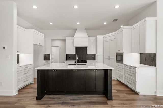 kitchen with white cabinets, a spacious island, black microwave, and dark wood-type flooring