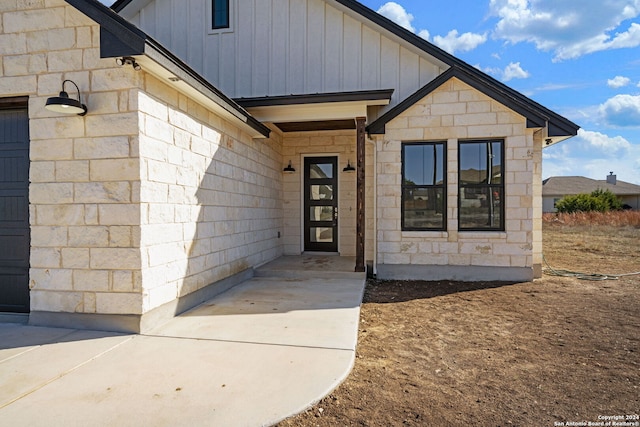 doorway to property featuring stone siding and board and batten siding