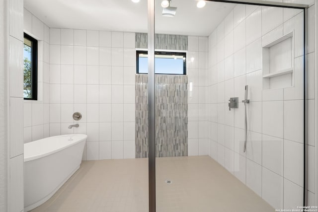 bathroom featuring plenty of natural light, separate shower and tub, and tile walls