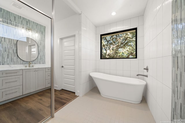 bathroom featuring a bathing tub, tile patterned flooring, vanity, and tile walls