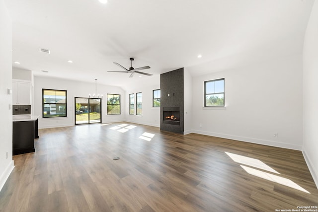 unfurnished living room featuring a large fireplace, ceiling fan with notable chandelier, wood-type flooring, and vaulted ceiling