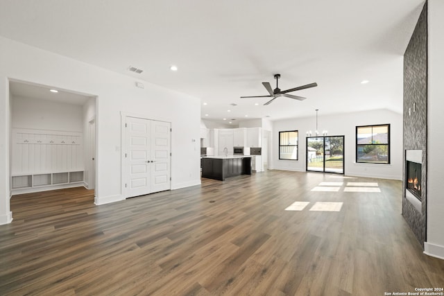 unfurnished living room with a fireplace, ceiling fan with notable chandelier, dark wood-type flooring, and sink